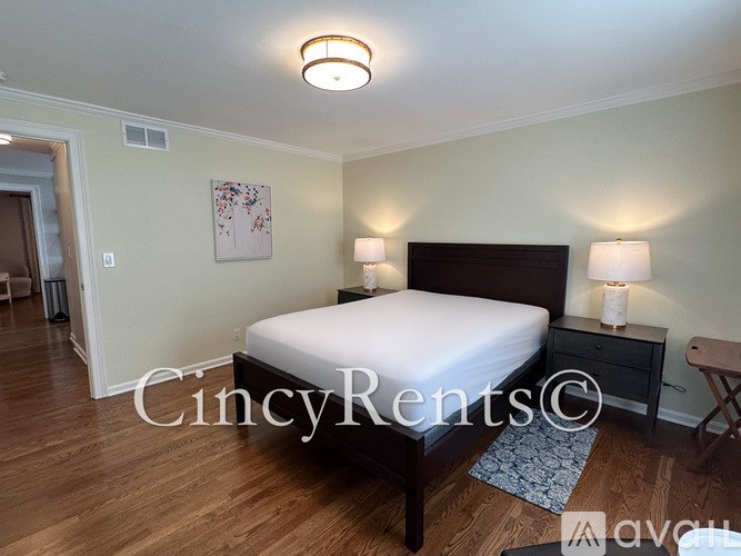 A bedroom with a bed, nightstands, and a painting on the wall.