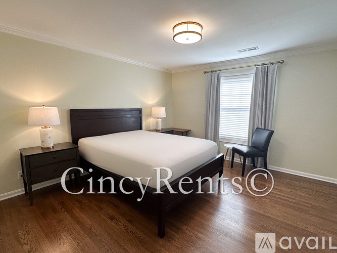 A bedroom with a bed, chair, and two lamps.