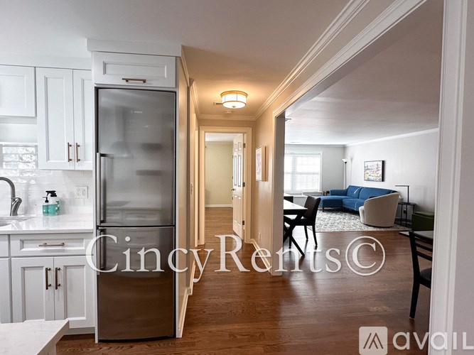 A kitchen with a refrigerator and a dining table with chairs.