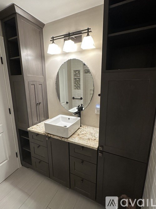 A bathroom with a sink, mirror, and cabinets.