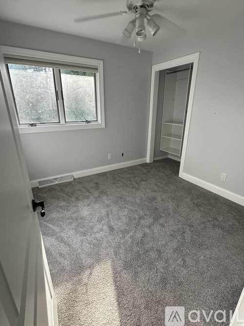 A room with a ceiling fan and a window.