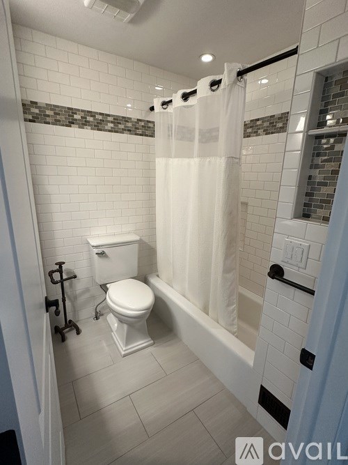 A white toilet is in a bathroom with a white shower curtain.