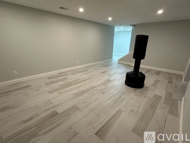 A room with wooden flooring and a speaker on a stand.