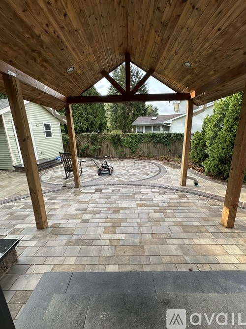 A patio with a wooden roof and brick flooring.