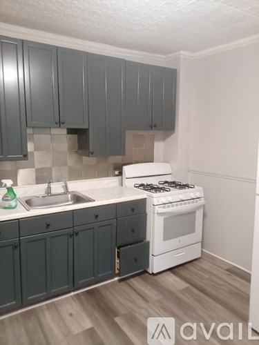 A kitchen with a white stove and grey cabinets.