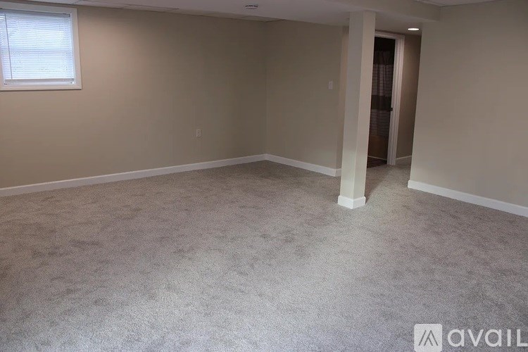 A room with a carpeted floor and a window with blinds.