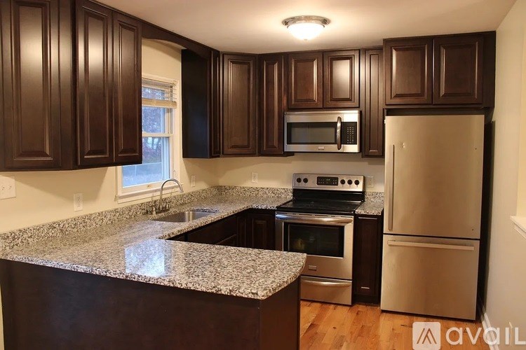 A kitchen with dark brown cabinets and granite countertops.