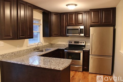 A kitchen with dark brown cabinets and granite countertops.