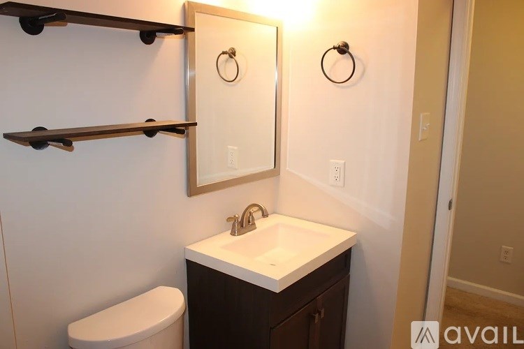 A bathroom with a toilet, sink, and mirror.