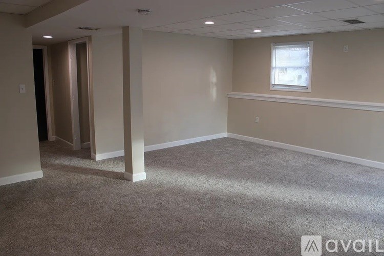 A room with a carpeted floor and a window with blinds.
