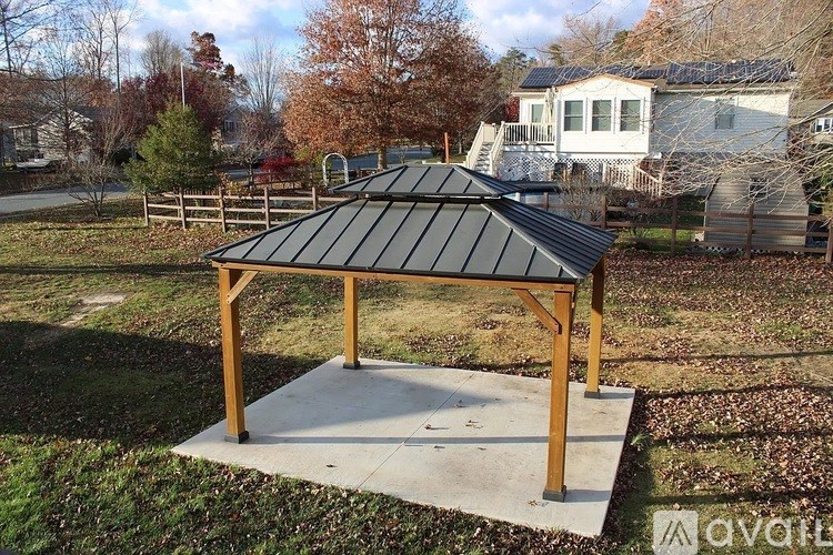 A gazebo with a black roof is situated in a grassy area.