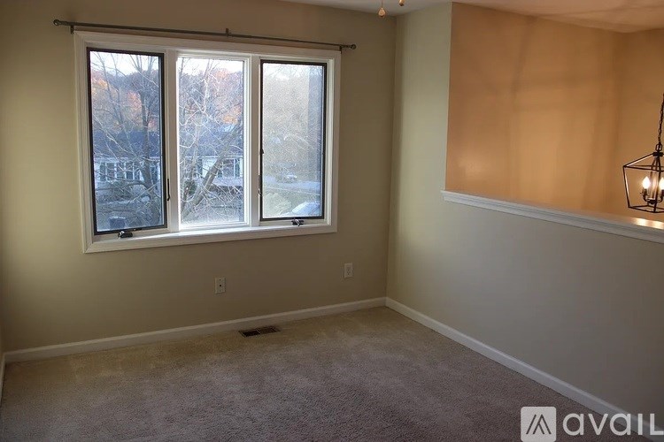A room with a window and a carpeted floor.