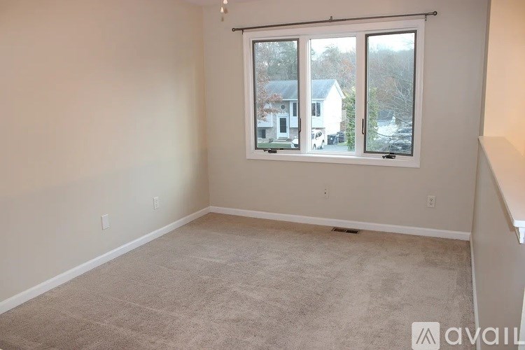 A room with a carpeted floor and a window showing a view of a house.