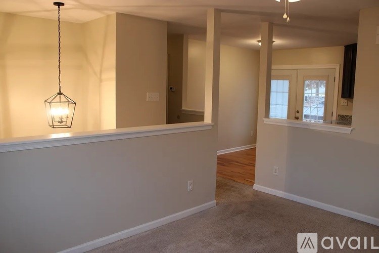 A room with a hanging light fixture and a window.