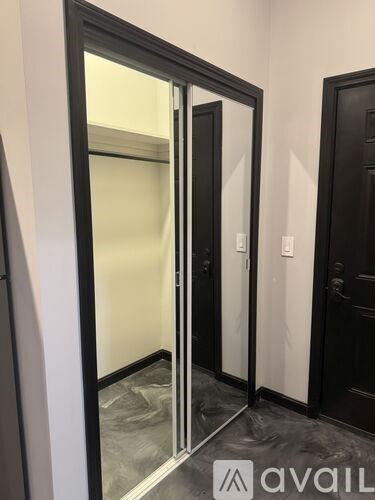 A black door with a glass panel and a white light switch on the wall.