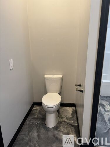 A white toilet in a small bathroom with a marble floor.