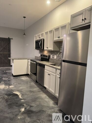 A kitchen with a stainless steel refrigerator, microwave, and oven.