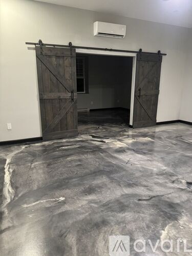 A room with a grey floor and a wooden door.