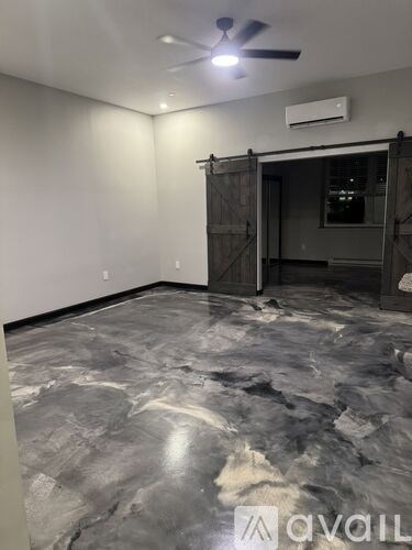 A room with a grey marble floor and a ceiling fan.