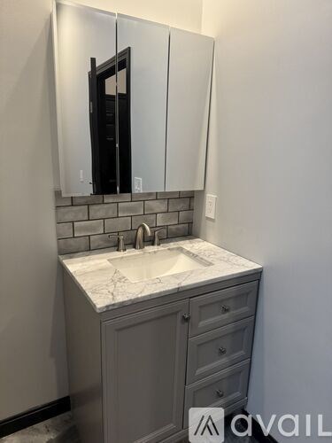 A bathroom vanity with a marble countertop and a mirror above it.