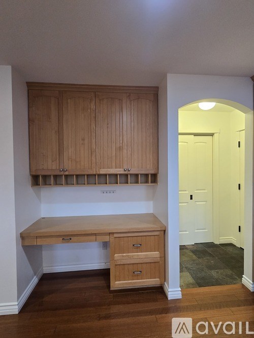 A room with a desk and drawers under a cabinet.