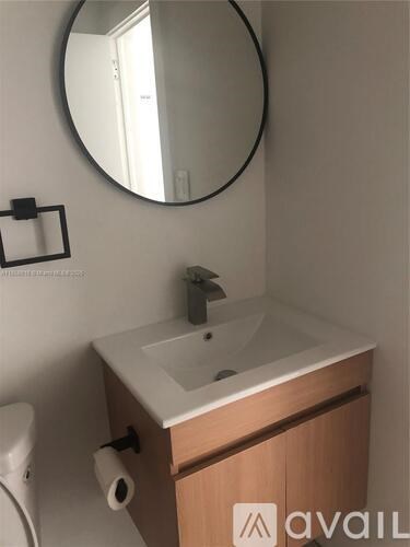 A bathroom with a sink, mirror, and toilet paper holder.