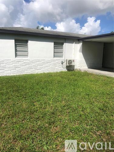 A white house with a grey roof and a green lawn in front.