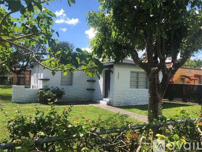 A white house with a tree in front of it.