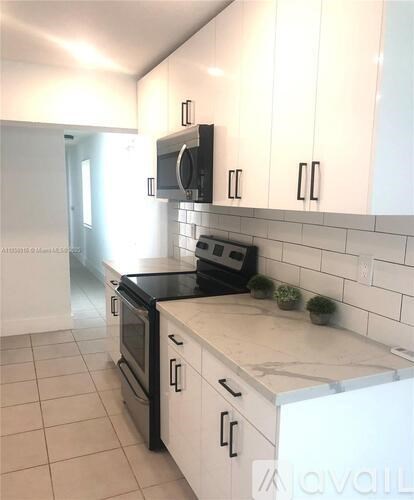 A kitchen with white cabinets and a black stove top.