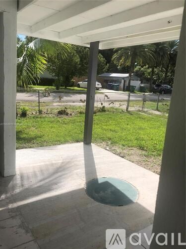 A view from a covered walkway looking out to a green yard.