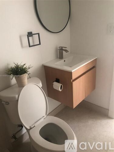 A bathroom with a toilet, sink, and mirror.