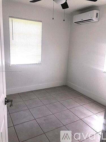 A room with a window, tiled floor, and a ceiling fan.