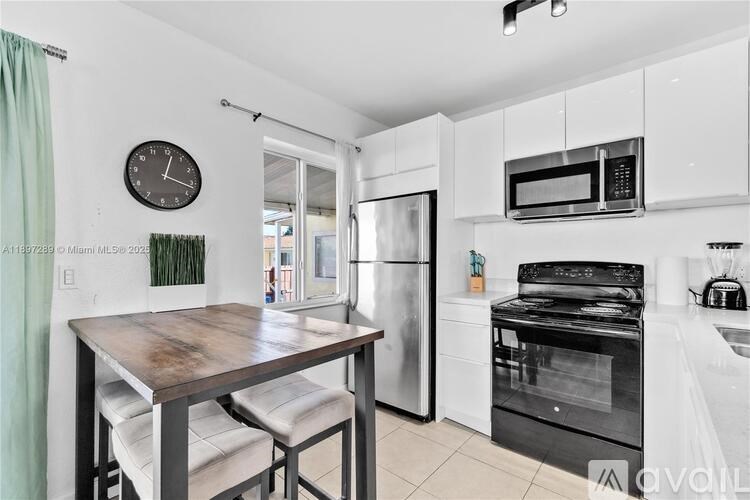 A kitchen with a table and chairs and a clock on the wall.