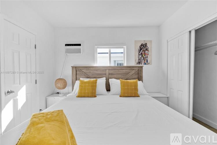 A bedroom with a bed, two yellow pillows, and a window.