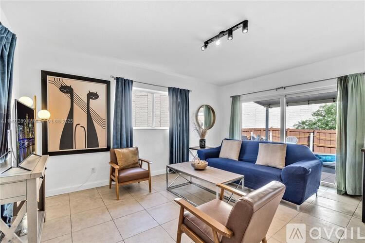 A living room with a blue couch and a painting on the wall.