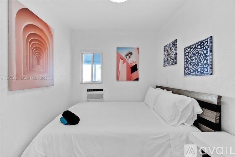 A bedroom with a white bed and a large painting on the wall.