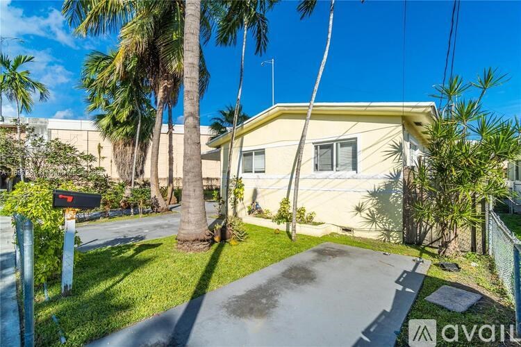 A house with a driveway and palm trees in front.