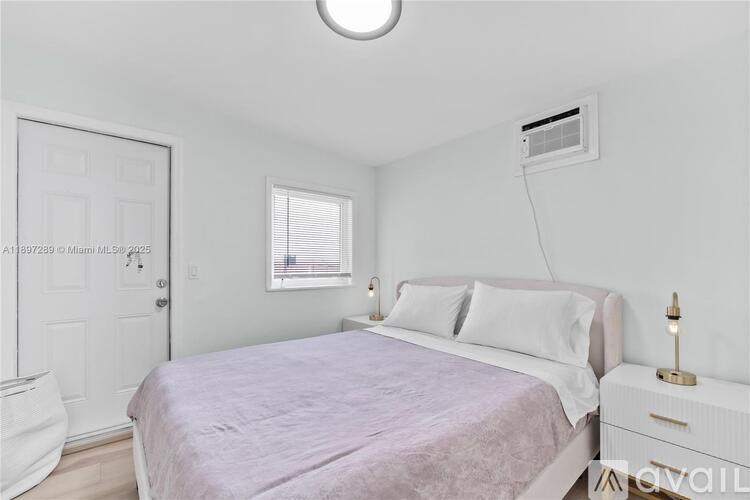 A bedroom with a bed, nightstand, and window.