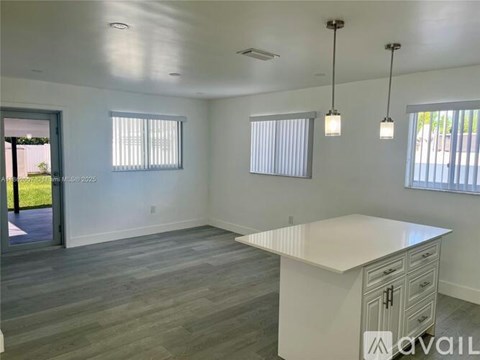 A spacious kitchen with a white countertop and grey flooring.