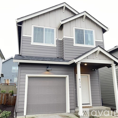 A two-story house with a garage door and a front door.