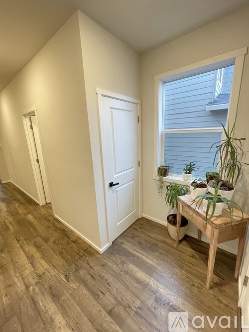 A room with a white door and a window with plants on a table.