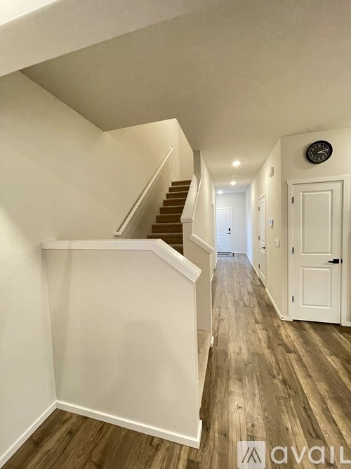 A hallway with a staircase and a clock on the wall.