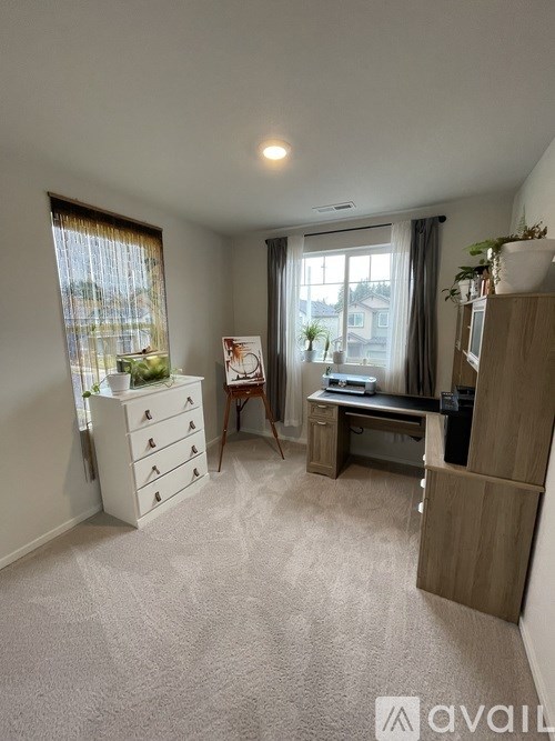 A well-lit, carpeted room with a desk, drawers, and a window.