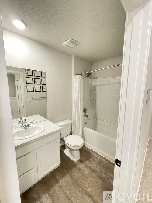 A white bathroom with a toilet, sink, and shower.