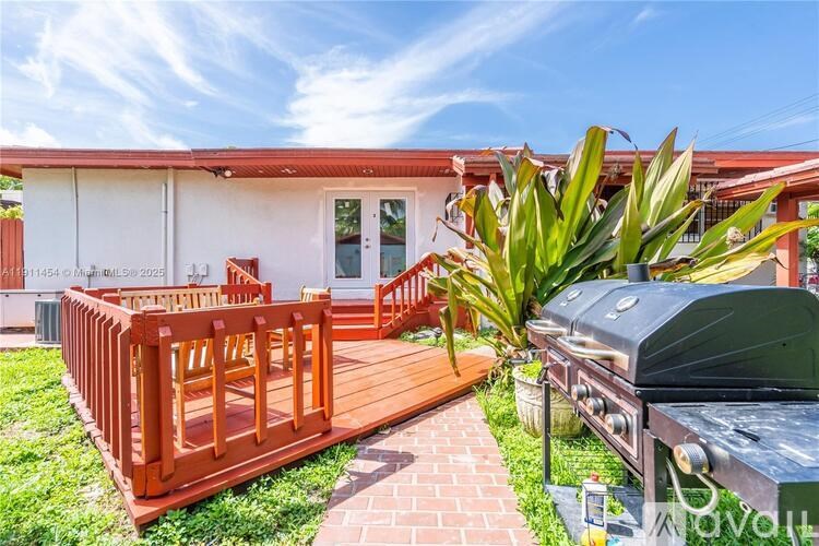 A red and white building with a wooden deck and a grill.