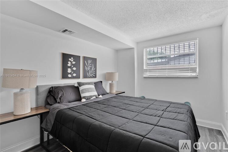 A bedroom with a large bed and a window with blinds.