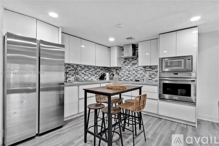 A modern kitchen with stainless steel appliances and a dining table set for two.