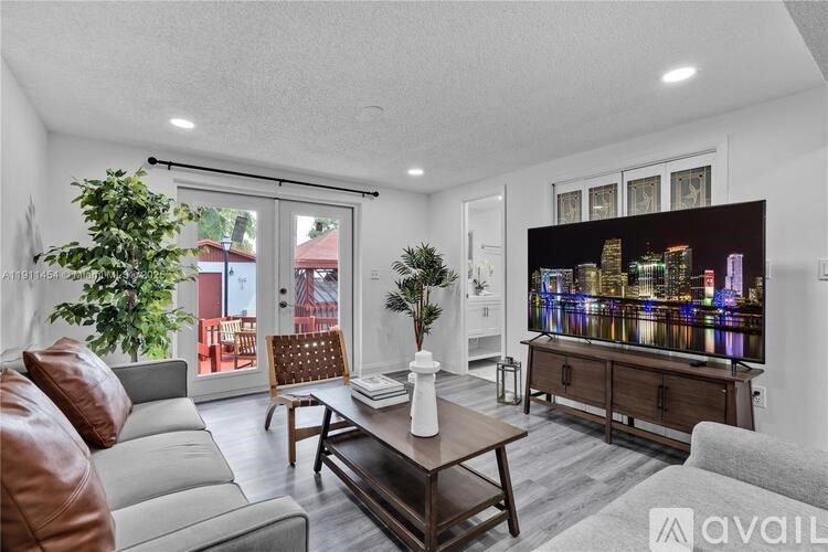 A living room with a brown leather couch, a wooden coffee table, and a large flat screen TV mounted on the wall.