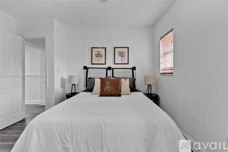 A bedroom with a large bed and two framed pictures on the wall.