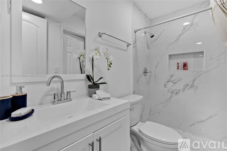 A white bathroom with a marble wall and a white toilet.